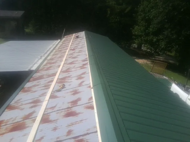 Old rusted panels beside newly installed green metal roofing — Wind Damage Roof Repair by Roofing Brothers in Josephine