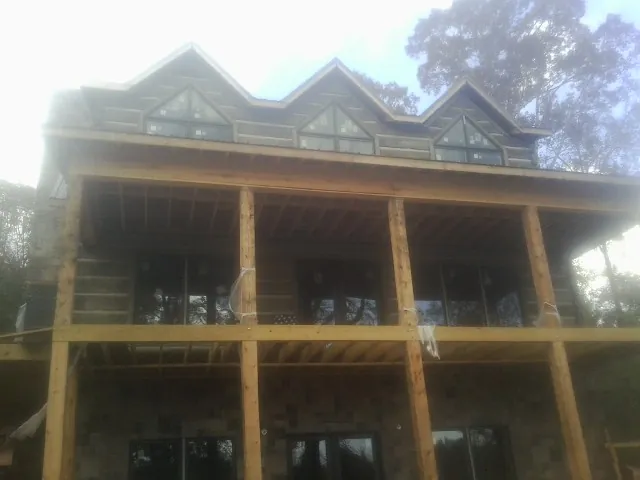 Dormers and porch framing on a large log home under construction — Roof Coating work by our crew in Josephine