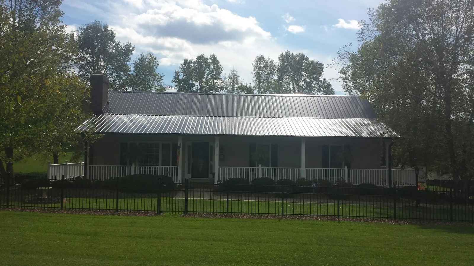 Gray metal roof on a brick ranch with a full width front porch — Gutter Guard Installation work by our crew in Josephine